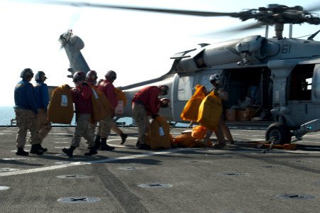 US Navy 120130-N-KS651-078 Sailors aboard the amphibious dock landing ship USS Pearl Harbor (LSD 52) unload mail from an MH-60S Sea Hawk helicopter