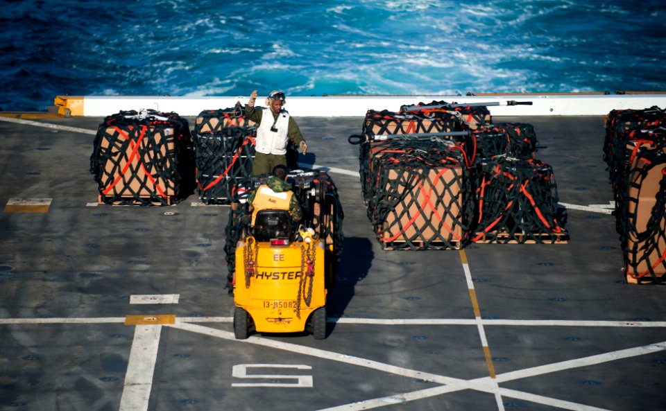 US Navy 120129-N-PB383-560 Master Sgt. Joseph Kelly guides Aviation Boatswain's Mate (Handling) 2nd Class Mark Thornton as he transfers cargo on th