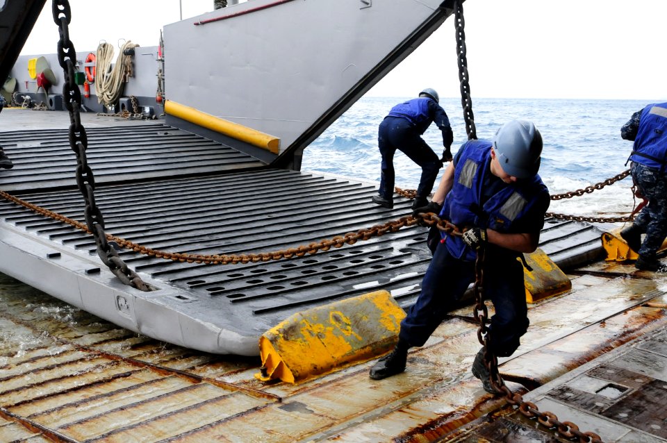US Navy 120202-N-WV964-073 Seaman Brandon Snook removes chains from a landing craft utility in the well deck of the forward-deployed amphibious doc
