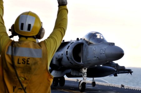 US Navy 120201-N-UM734-306 An aviation boatswain's mate directs the landing of an AV-8B Harrier from Marine Attack Squadron (VMA) 542 on the flight