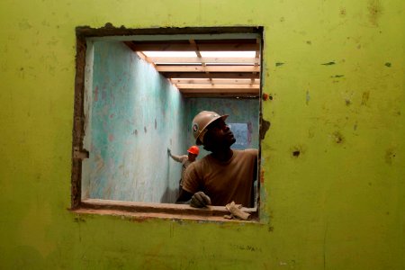US Navy 120201-A-IP644-078 Equipment Operator 2nd Class Tyrif Wells and Peruvian combat engineers smooth the walls at Escuela Pronoie Nuevo Desper
