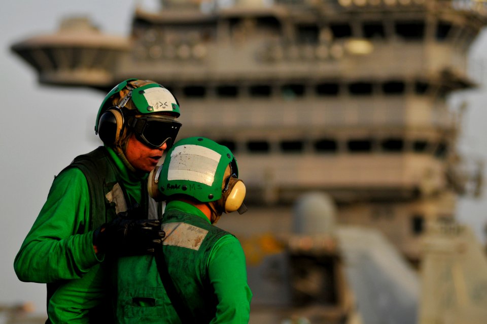 US Navy 120201-N-ZI635-177 Aviation Boatswain's Mate (Equipment) 2nd Class Enrico Balmaceda talks with another Sailor before flight operations aboa