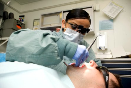 US Navy 120131-N-JN664-031 Hospital Corpsman 1st Class Laura Blanco cleans Electrician's Mate 1st Class Cory Hartley's teeth aboard the Nimitz-cla photo