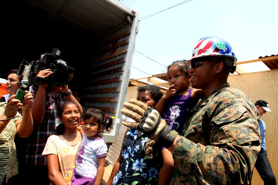 US Navy 120201-A-IP644-126 Staff Sgt. Garival Perez holds a girl for a Peruvian news team during HSV-Southern Partnership Station 2012 outside an e