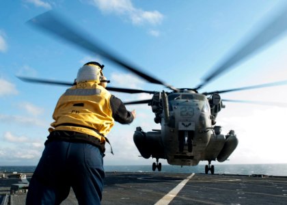 US Navy 120202-N-NR955-056 Boatswain's Mate 2nd Class Trevaughn M. Green, a landing signalman enlisted, guides a CH-53E Super Stallion helicopter a