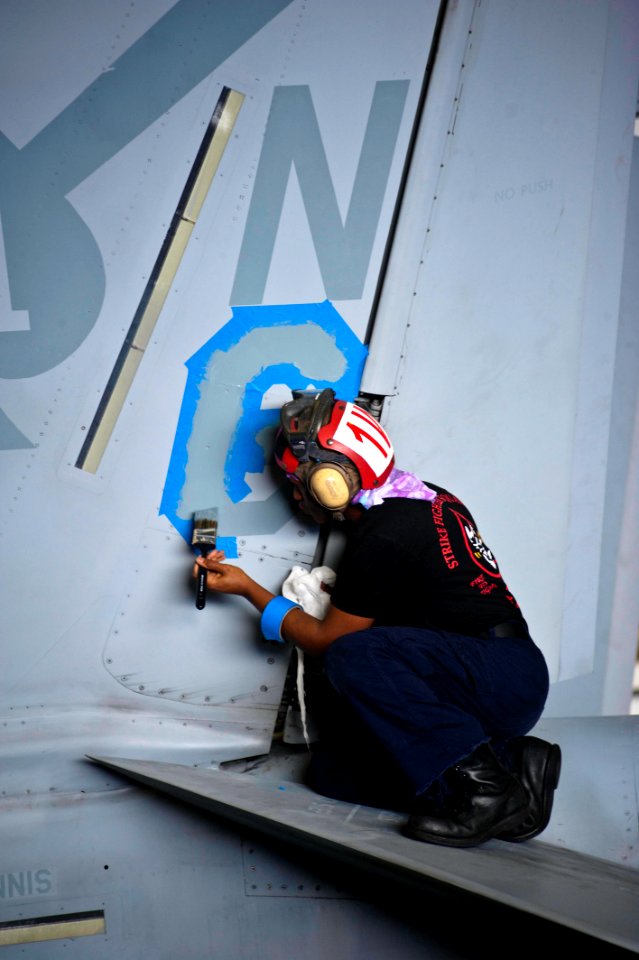US Navy 120206-N-GC412-466 Airman James Rice paints the squadron designator on the vertical stab on an F-A-18F Super Hornet from the Black Aces of