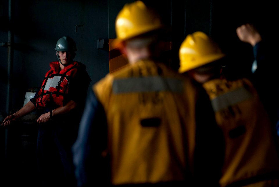 US Navy 120202-N-DR144-198 Boatswain's Mate Seaman Payne Ivie listens to commands from rig captains while manning a line in the hangar bay aboard t
