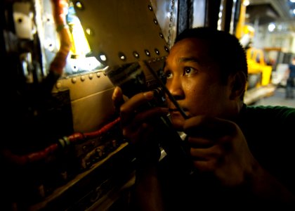 US Navy 120204-N-BT887-178 Aviation Structural Mechanic (Equipment) 3rd Class Jasper Cruz searches for a screw in the engine compartment of an F-A