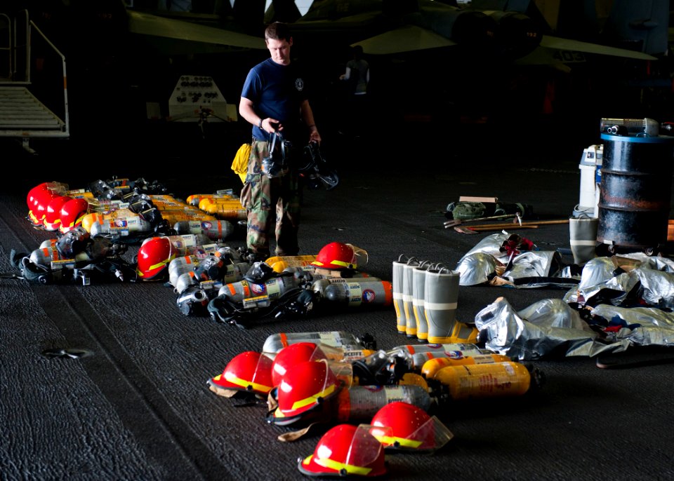 US Navy 120204-N-BT887-043 Aviation Boatswain's Mate (Handling) Airman Zachary Hickman stows firefighting equipment in the hangar bay aboard the Ni
