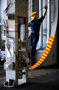 US Navy 120206-N-XE109-078 Boatswain's Mate 3rd Class Shadi K. Azhari checks the slack of a sliding pad eye wire in the hangar bay aboard the Nimit