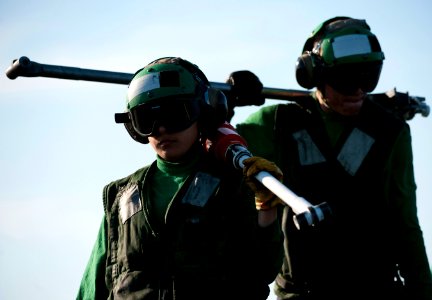 US Navy 120207-N-DR144-556 Sailors carry holdback bars off the flight deck after launching aircraft