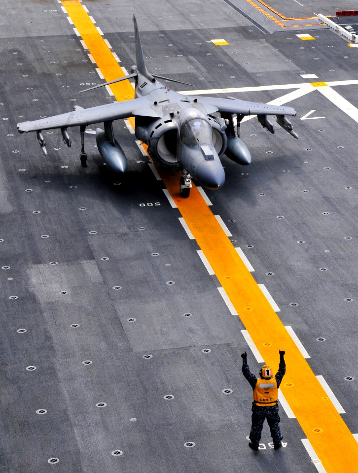 US Navy 120207-N-KB563-097 An aviation boatswain's mate (handler) taxis an AV-8B Harrier across the flight deck of the amphibious assault ship USS