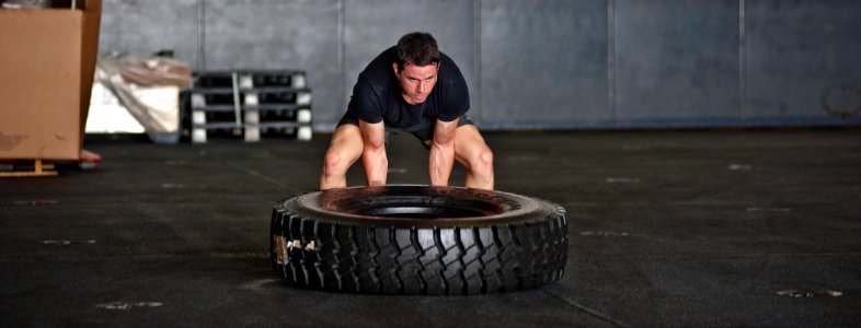 US Navy 120206-N-GC412-386 Airman Mario Rojas flips a truck tire in the hangar bay while exercising aboard the Nimitz-class aircraft carrier USS Jo