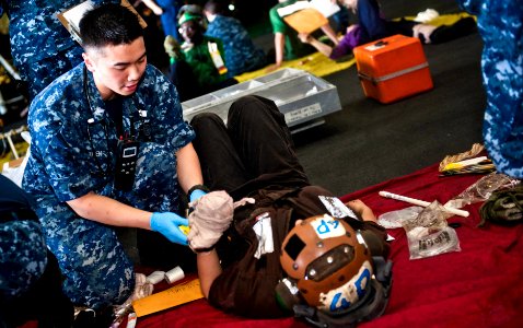 US Navy 120209-N-GC412-470 Hospital Corpsman 2nd Class Henry Nguyen treats a Sailor for simulated injuries during a mass casualty drill in the hang