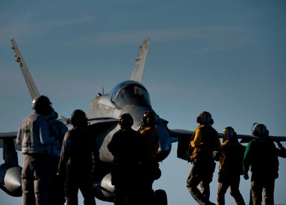 US Navy 120207-N-DR144-619 An F-A-18C Hornet assigned to Strike Fighter Squadron (VFA) 25 taxis past Sailors working on the flight deck aboard the