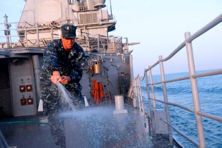 US Navy 120206-N-VY256-108 A Sailor washes the fantail of USS Cape St. George