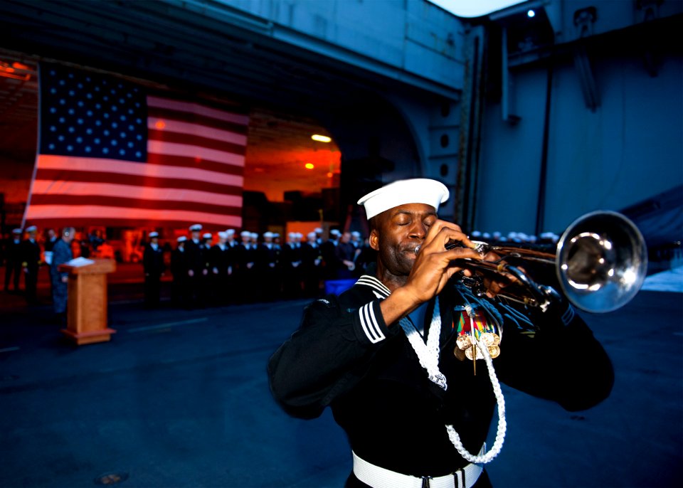 US Navy 120207-N-FI736-006 Boatswain's Mate 1st Class Timothy Lumpkin plays Taps during a burial at sea ceremony aboard the aircraft carrier USS En