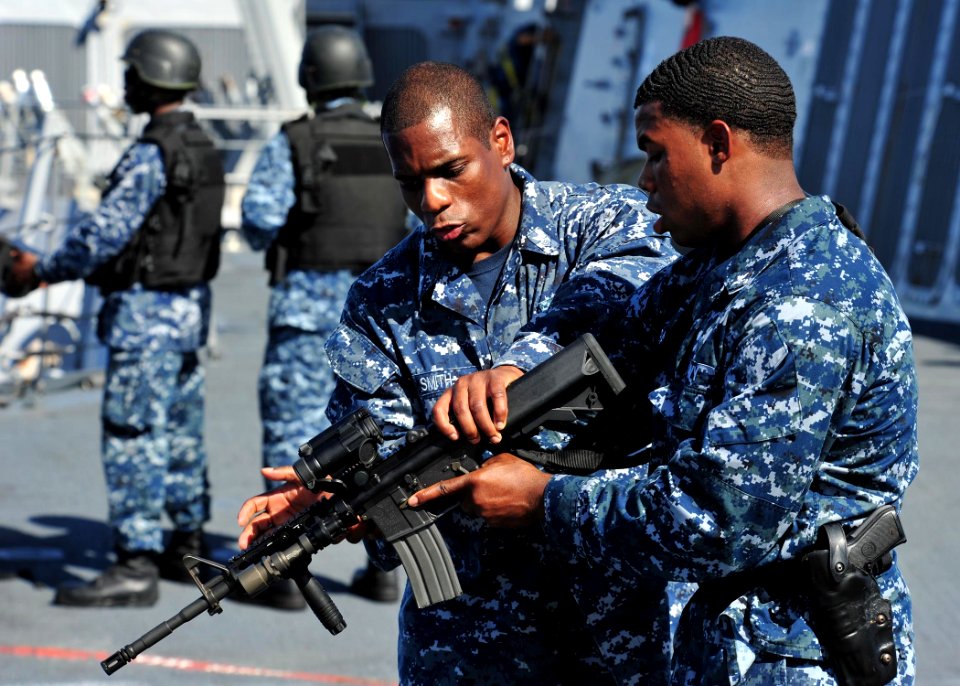 US Navy 120210-N-ED900-983 Personnel Specialist 1st Class Dwayne Smith, left, gives weapons familiarization training on the M4-A1 carbine to Operat