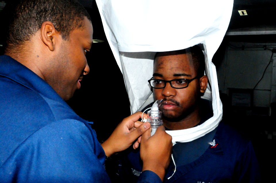 US Navy 120214-N-WV964-009 Information Technician 2nd Class Raymond Jackson performs a respiratory fitting test on Hull Technician 3rd Class Adrine
