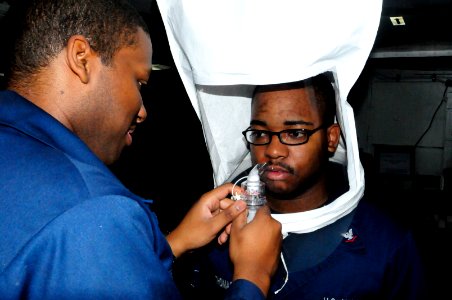 US Navy 120214-N-WV964-009 Information Technician 2nd Class Raymond Jackson performs a respiratory fitting test on Hull Technician 3rd Class Adrine