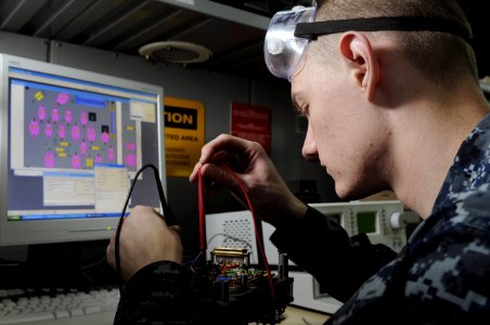 US Navy 120215-N-RG587-184 Electronics Technician 3rd Class Chris Elmendorf tests the connectivity of a circuit board in the micro-miniature repair