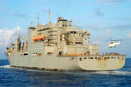 USNS Amelia Earhart performs a vertical replenishment while sailing alongside the USS Normandy