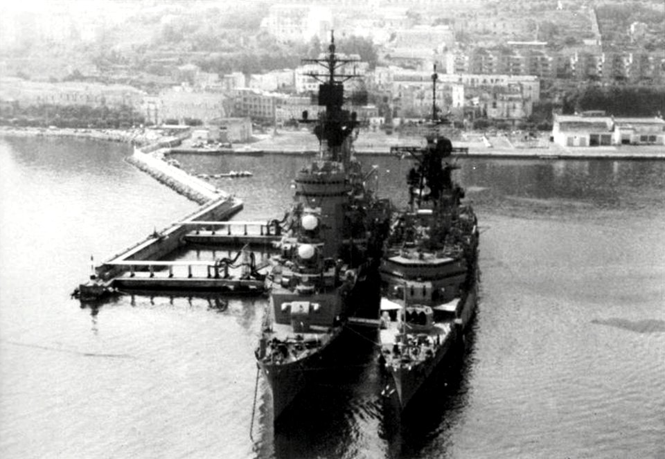 USS Little Rock (CG-4) and USS Albany (CG-10) docked at the refueling pier at Geata, Italy, 1976