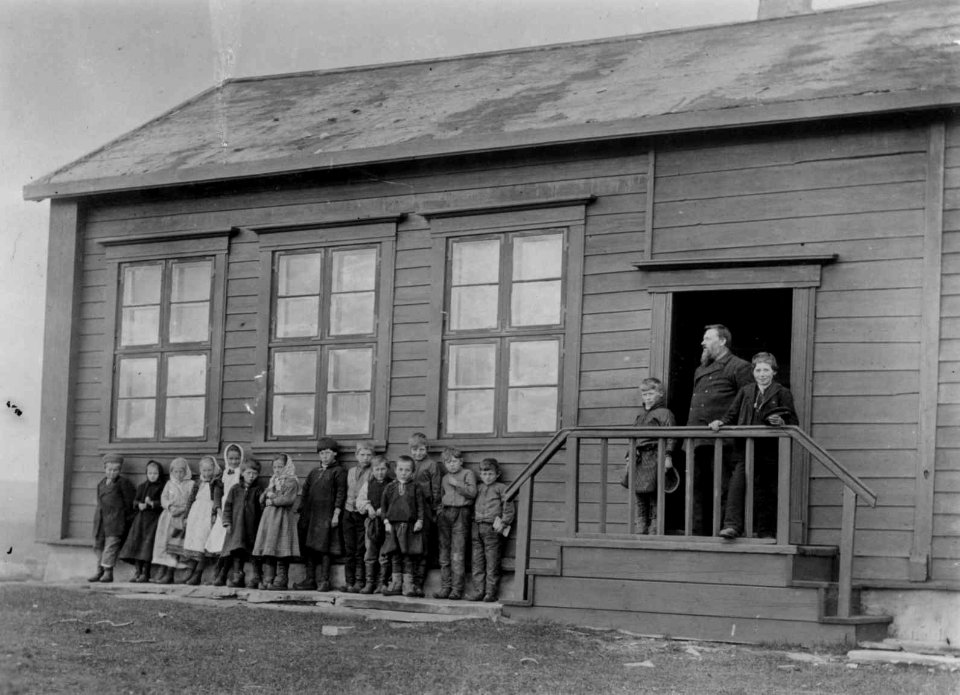 Vestre Jakobselvs første skole, Vadsø, Finnmark. Lærer Thomas Lilleeng med sine elever foran skolen - Norsk folkemuseum - NF.05063-043