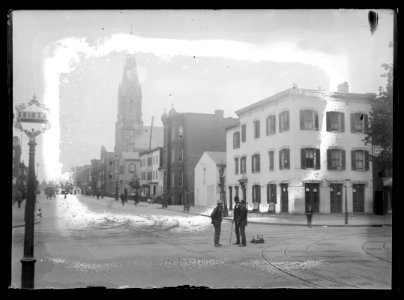 View of 5th Street, N.W., East side, looking North from G Street with two men standing in the street conversing and steeple from St. Mary's Catholic Church can be seen standing high above LCCN2016646844 photo