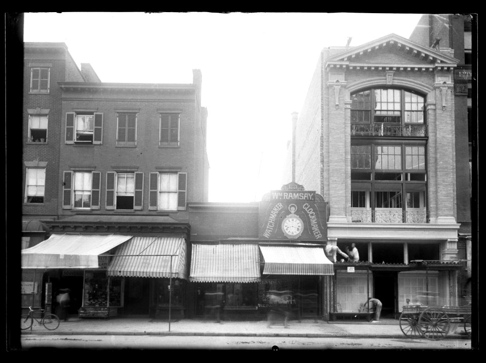 View of F Street, N.W., North side, between 12th & 13th Streets showing various businesses fronts along the block; workers repairing building LCCN2016647052