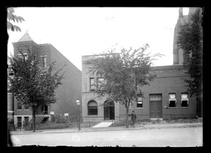 View of man standing in front of possibly the C & P Telephone Co. on unidentified street; name of building obscured by tree LCCN2016647126 photo