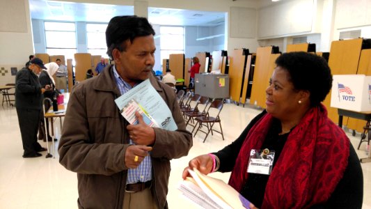 Virginia voter gets election materials from polling station worker before voting in US presidential election, Nov. 8, 2016 photo