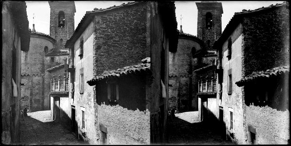 Vista d'un carrer , al fons l'absis i el campanar de l'església
