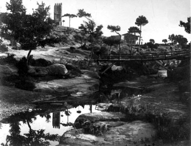 Vista d'una masia amb pont i riu en primer terme i una torre a Santa Maria de Merola