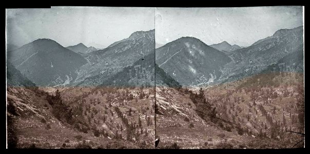 Vista general d'una vall amb poca vegetació i muntanyes al fons