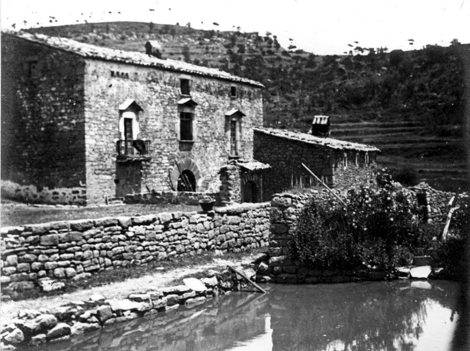 Vista general de l'Hostal del Boix amb una bassa d'aigua en primer terme