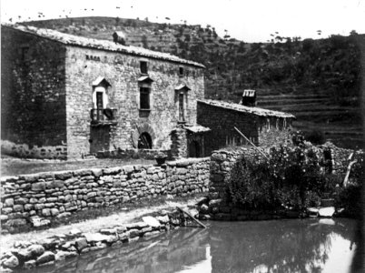 Vista general de l'Hostal del Boix amb una bassa d'aigua en primer terme