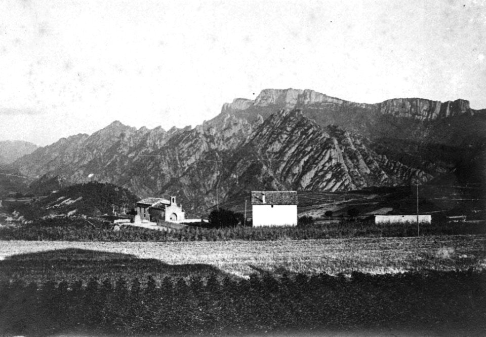 Vista llunyana de la Capella de la Pietat de Sant Llorenç de Morunys i les muntanyes al fons
