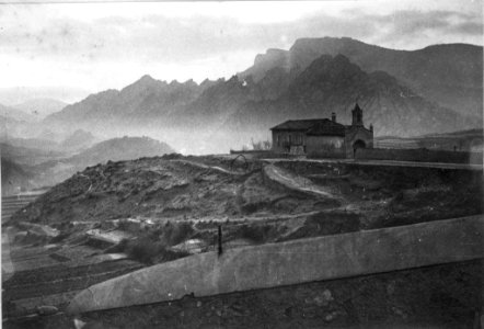 Vista llunyana de la Capella de la Pietat de Sant Llorenç de Morunys i les muntanyes al fons (AFCEC EMC X 6575)