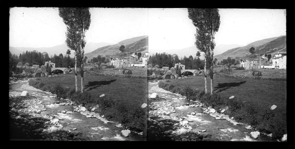 Vista parcial d'un poble , riu en primer terme i pont al fons