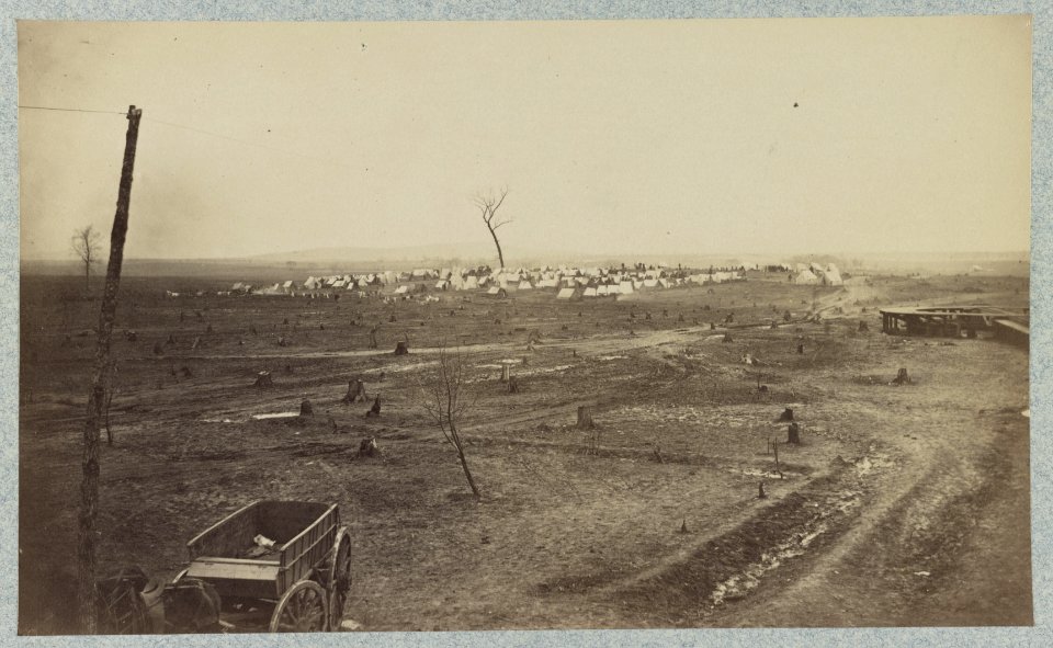Wagon parked near a telegraph pole in foreground with a camp in the background LCCN2012648030