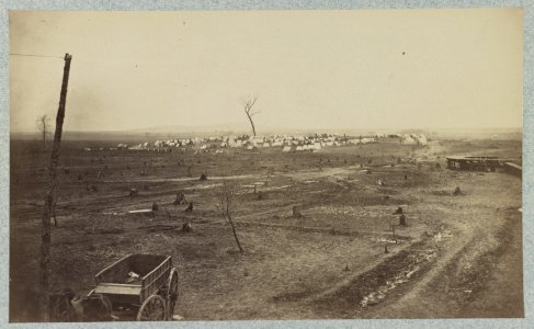Wagon parked near a telegraph pole in foreground with a camp in the background LCCN2012648030