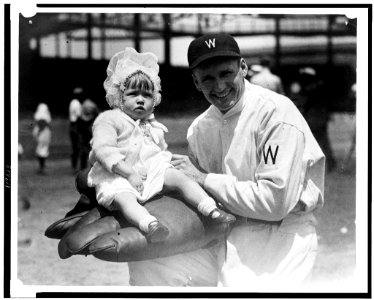 Walter Johnson, half-length portrait, facing slightly left, holding little girl on large glove LCCN93510964
