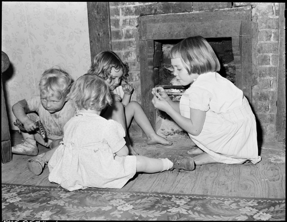 Wanda Lee and Bobbie Jean Sergent with neighborhood children crack nuts on the hearth in the living room of their... - NARA - 541313