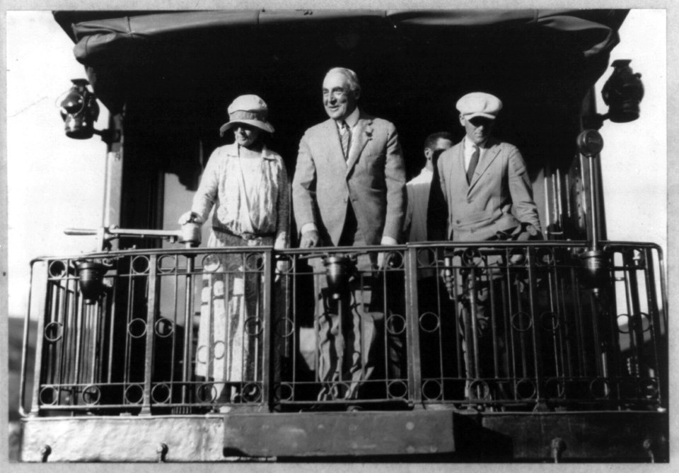 Warren G. Harding, full length portrait, standing on back of Northern Pacific train, facing left; with wife and Gardener, departing LCCN2005694590