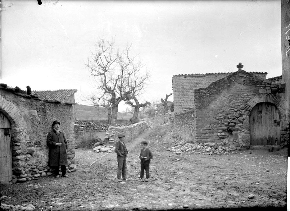 Un home i dos nens en un carrer de Barasona al costat de la porta del cementiri