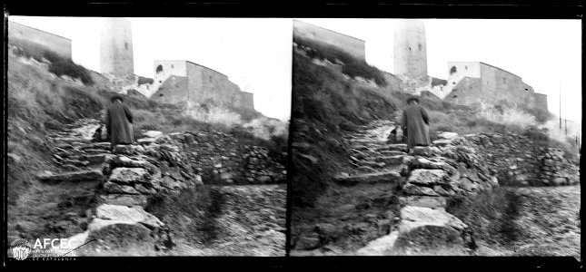 Un home en unes escales i al fons cases i la torre de Pinós