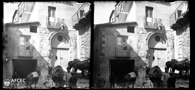 Un grup de nens, un home i diversos ases en una plaça davant de la porta de la capella de Santa Eulàlia