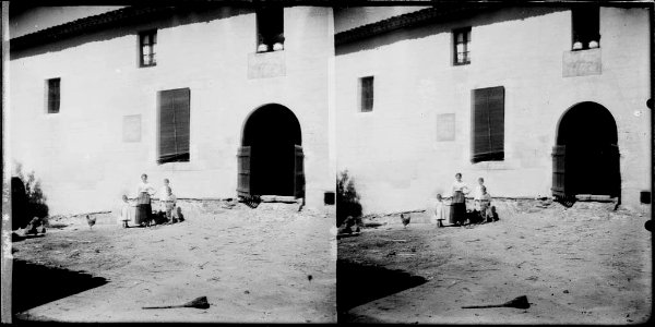 Una dona i alguns nens a l'era davant la façana de Can Via