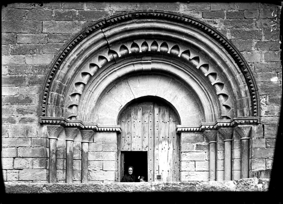 Una dona davant la portalada de l'església de Vinaixa
